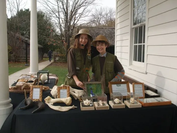 Young Dylan and his mom at a Creature Quest display table of skulls, bones and feathers