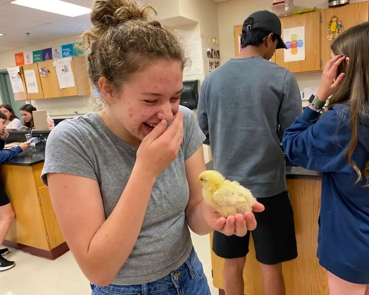 A high school student holding a chick